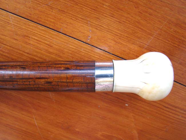 A 19th century rosewood walking stick with whale ivory knob and silver band engraved 'J.C. Rollins' circa 1860.